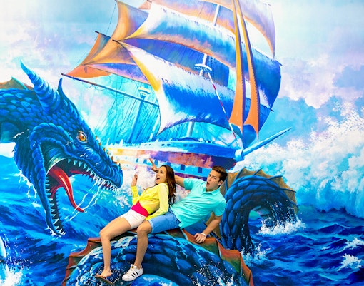 Couple interacting with 3D sea monster art at Trick Eye Museum.