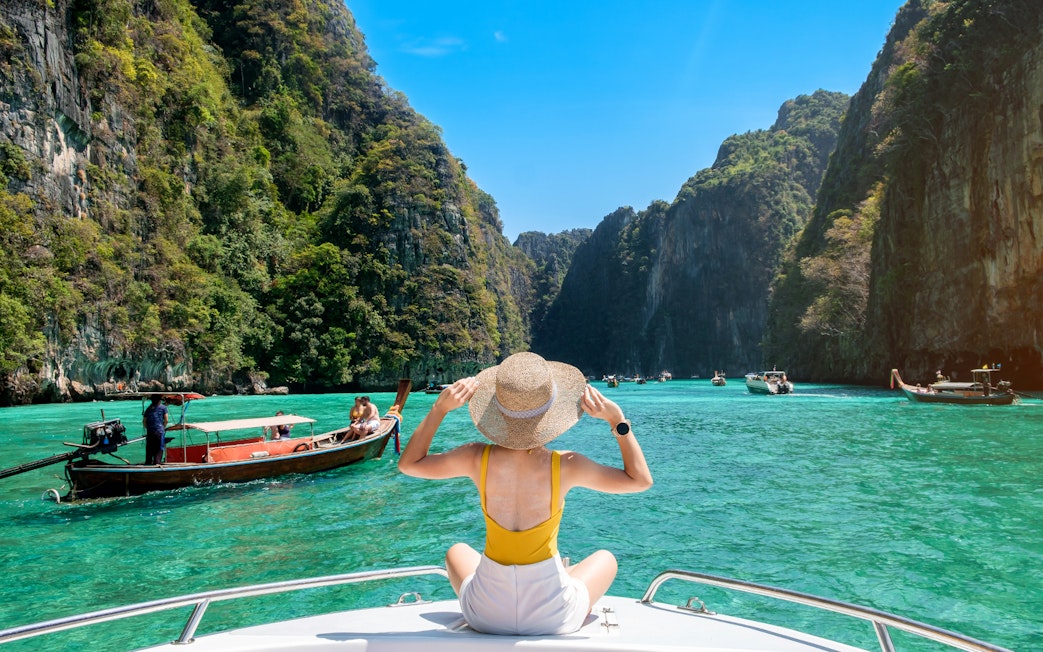 Woman on a boat admiring limestone cliffs at Phi Phi Island, Thailand.