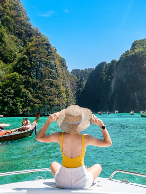 Woman on a boat admiring limestone cliffs at Phi Phi Island, Thailand.