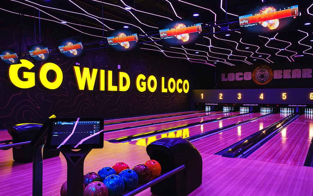 Bowling lanes at Loco Bear entertainment hub with neon "Go Wild Go Loco" sign.