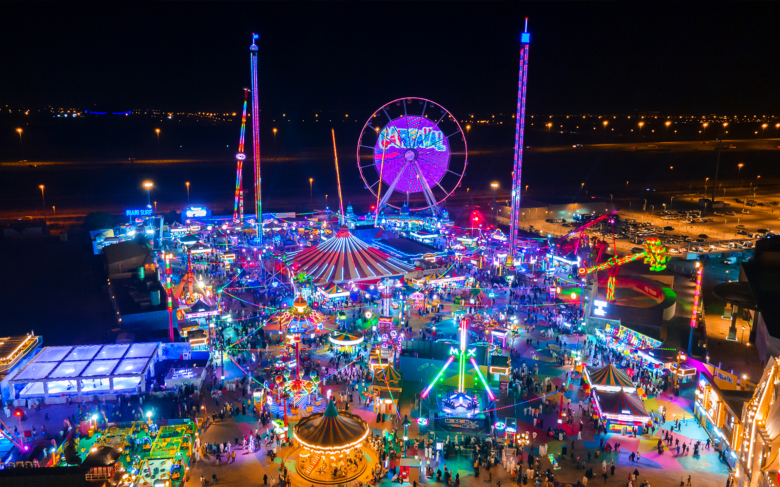 Aerial view of Global Village at night with colorful lights and attractions.