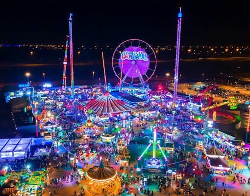 Aerial view of Global Village at night with colorful lights and attractions.