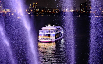 Cruise boat on Han River at night with city lights in the background.