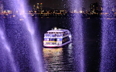 Cruise boat on Han River at night with city lights in the background.