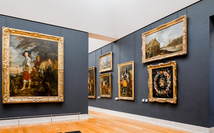 Louvre Museum gallery with classic paintings in ornate frames, Paris.