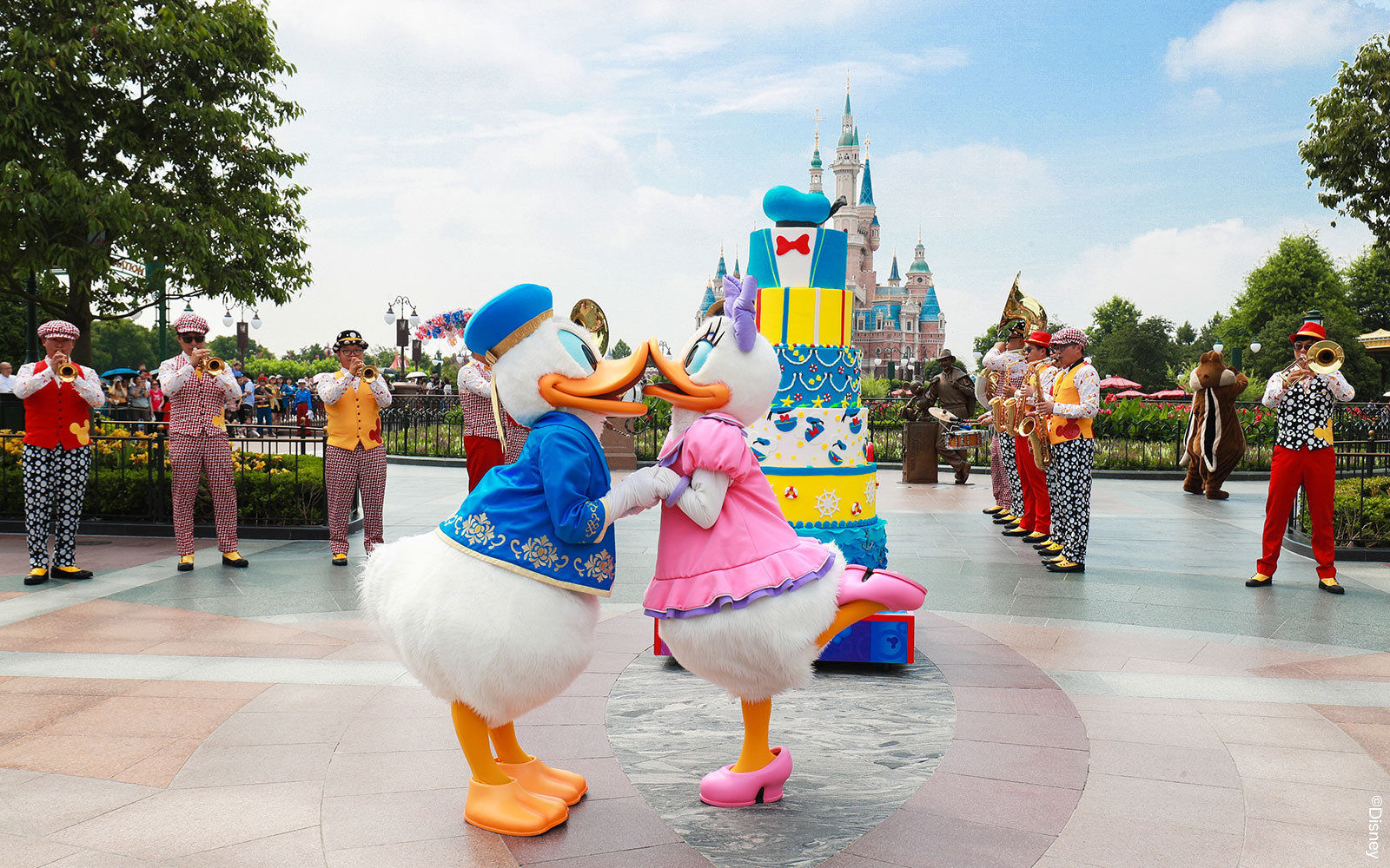 Donald and Daisy Duck dancing in front of a cake at Shanghai Disneyland with a band playing nearby.