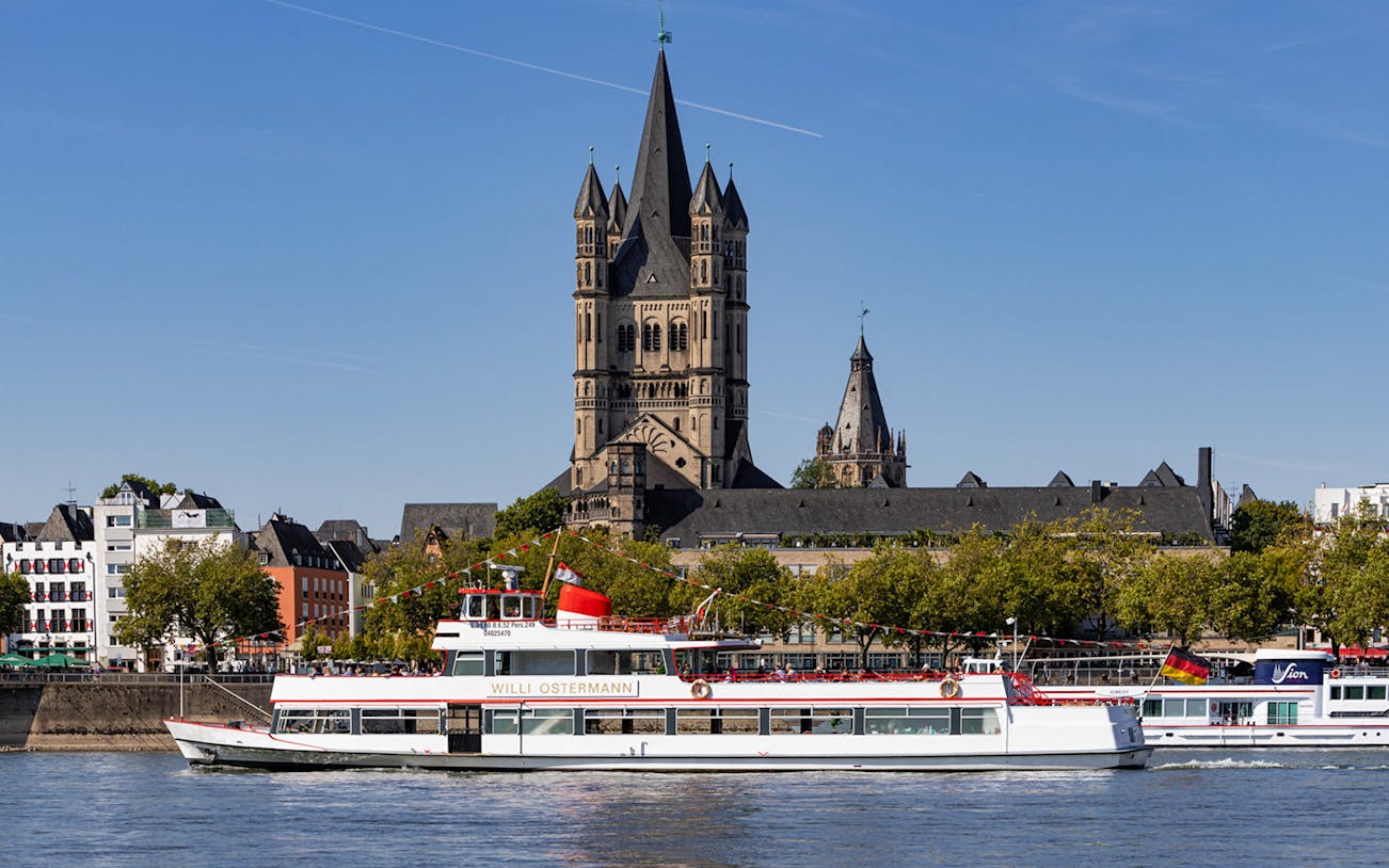 Cruise boat on the Rhine River with Cologne's Great St. Martin Church in the background.