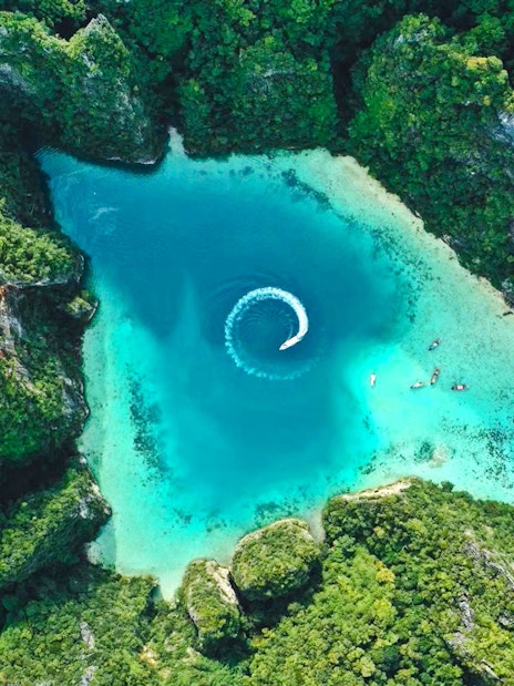 Aerial view of turquoise lagoon surrounded by lush cliffs in Phi Phi Islands, Thailand.