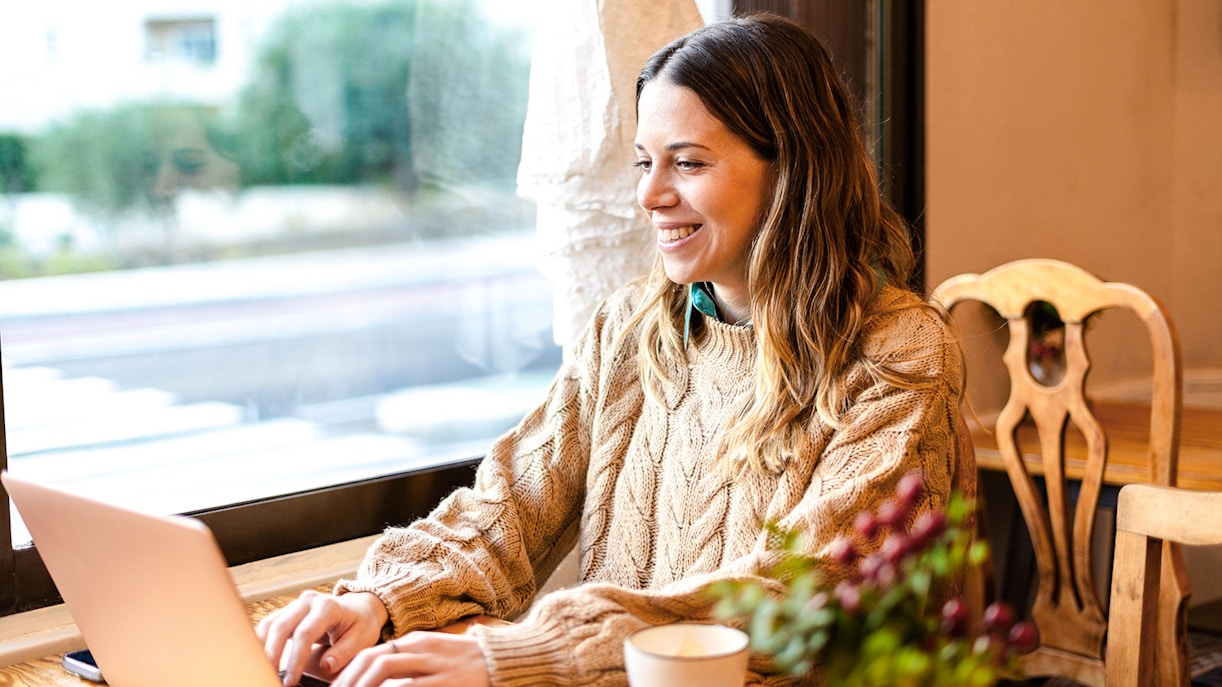 Digital nomad working on a laptop in a cozy cafe.