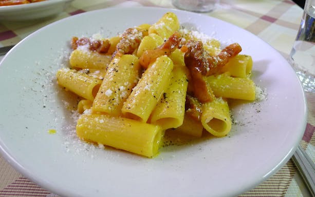 Rigatoni carbonara served on a plate during Trastevere food tour.
