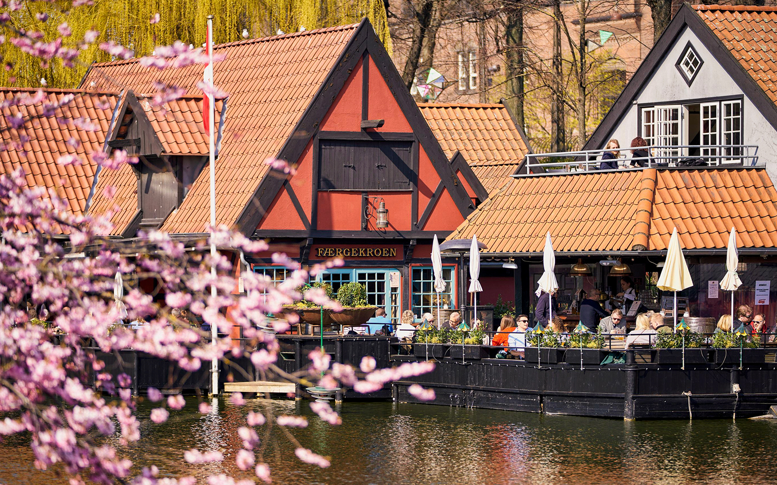 Tivoli Gardens lakeside restaurant with people dining outdoors in Copenhagen.