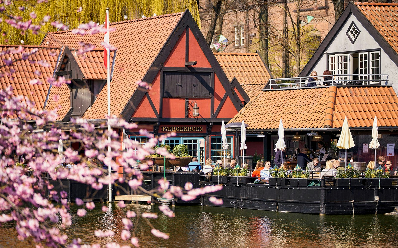 Tivoli Gardens lakeside restaurant with people dining outdoors in Copenhagen.