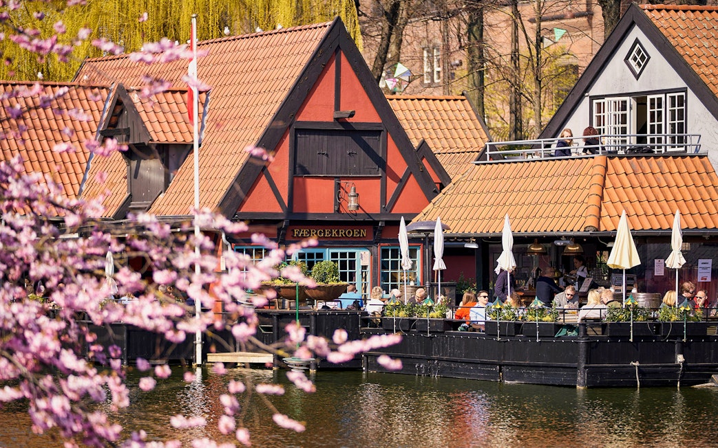 Tivoli Gardens lakeside restaurant with people dining outdoors in Copenhagen.
