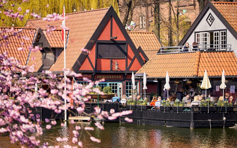 Tivoli Gardens lakeside restaurant with people dining outdoors in Copenhagen.