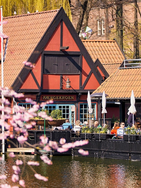 Tivoli Gardens lakeside restaurant with people dining outdoors in Copenhagen.