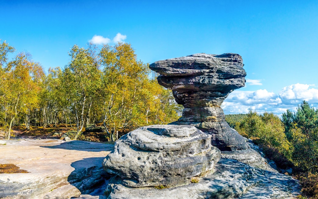 Sandstone formations at Tisa Rocks with surrounding forest under a clear blue sky.