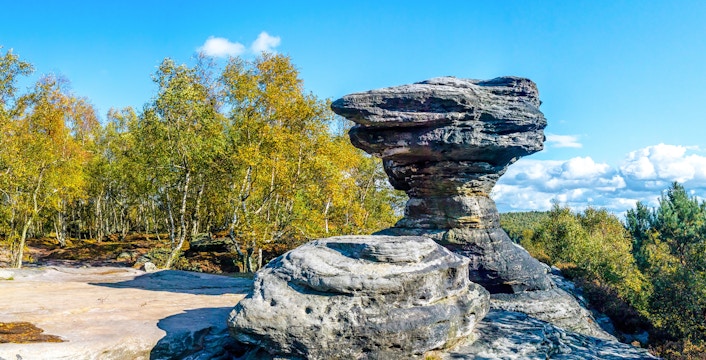 Sandstone formations at Tisa Rocks with surrounding forest under a clear blue sky.