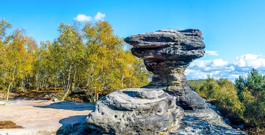 Sandstone formations at Tisa Rocks with surrounding forest under a clear blue sky.