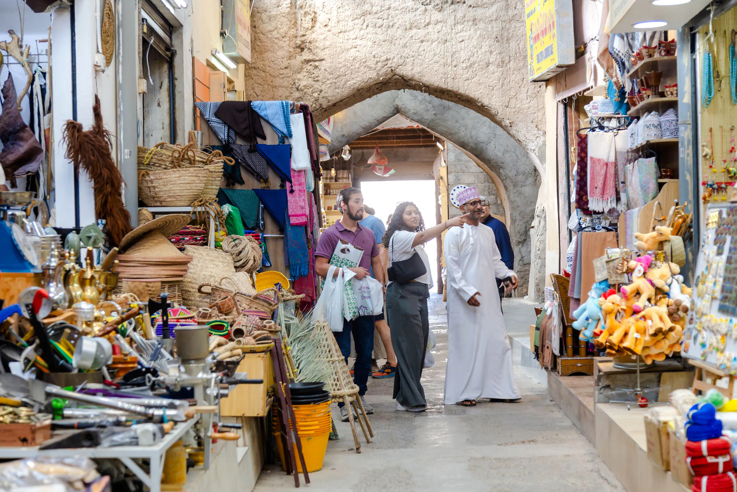 Nizwa market scene with tourists exploring local crafts and souvenirs, Oman.