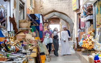 Nizwa market scene with tourists exploring local crafts and souvenirs, Oman.