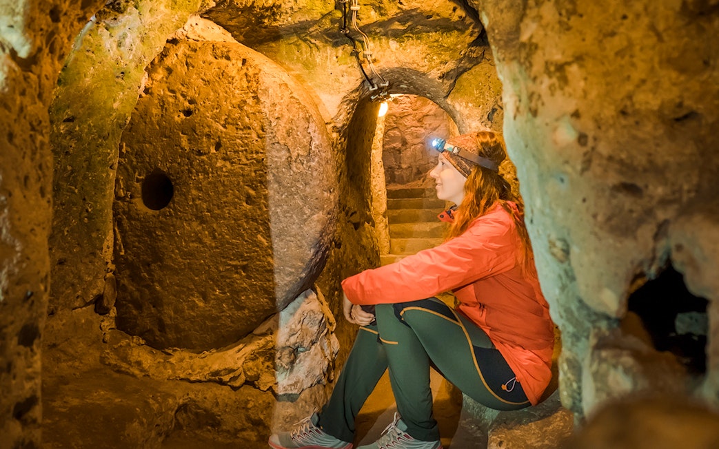 Young woman exploring Derinkuyu underground cave city in Turkey.