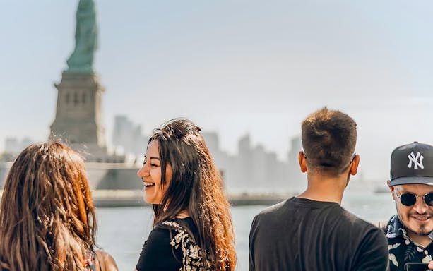 Visitors on ferry with Statue of Liberty in background, New York City.