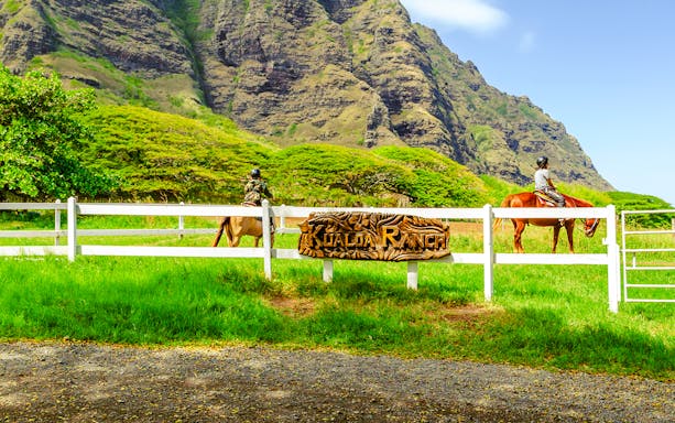 Horseback riders at Kualoa Ranch with lush mountains in Hawaii.