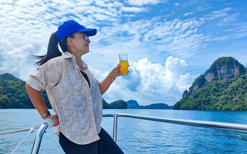 Woman enjoying juice on a lunch cruise with scenic ocean and island views.