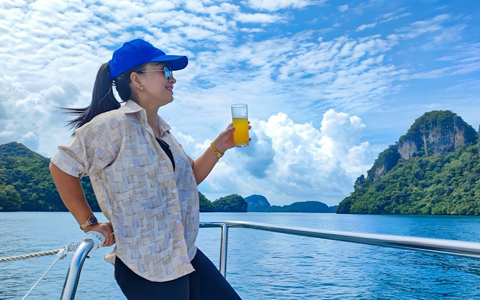 Woman enjoying juice on a lunch cruise with scenic ocean and island views.
