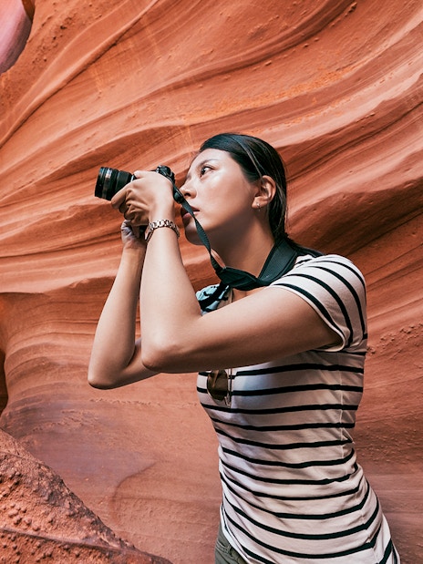 Woman photographing sandstone formations in Upper Antelope Canyon, Arizona.