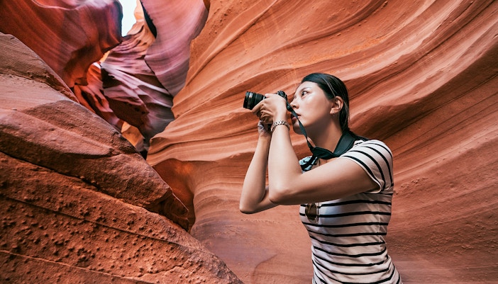 Woman photographing sandstone formations in Upper Antelope Canyon, Arizona.