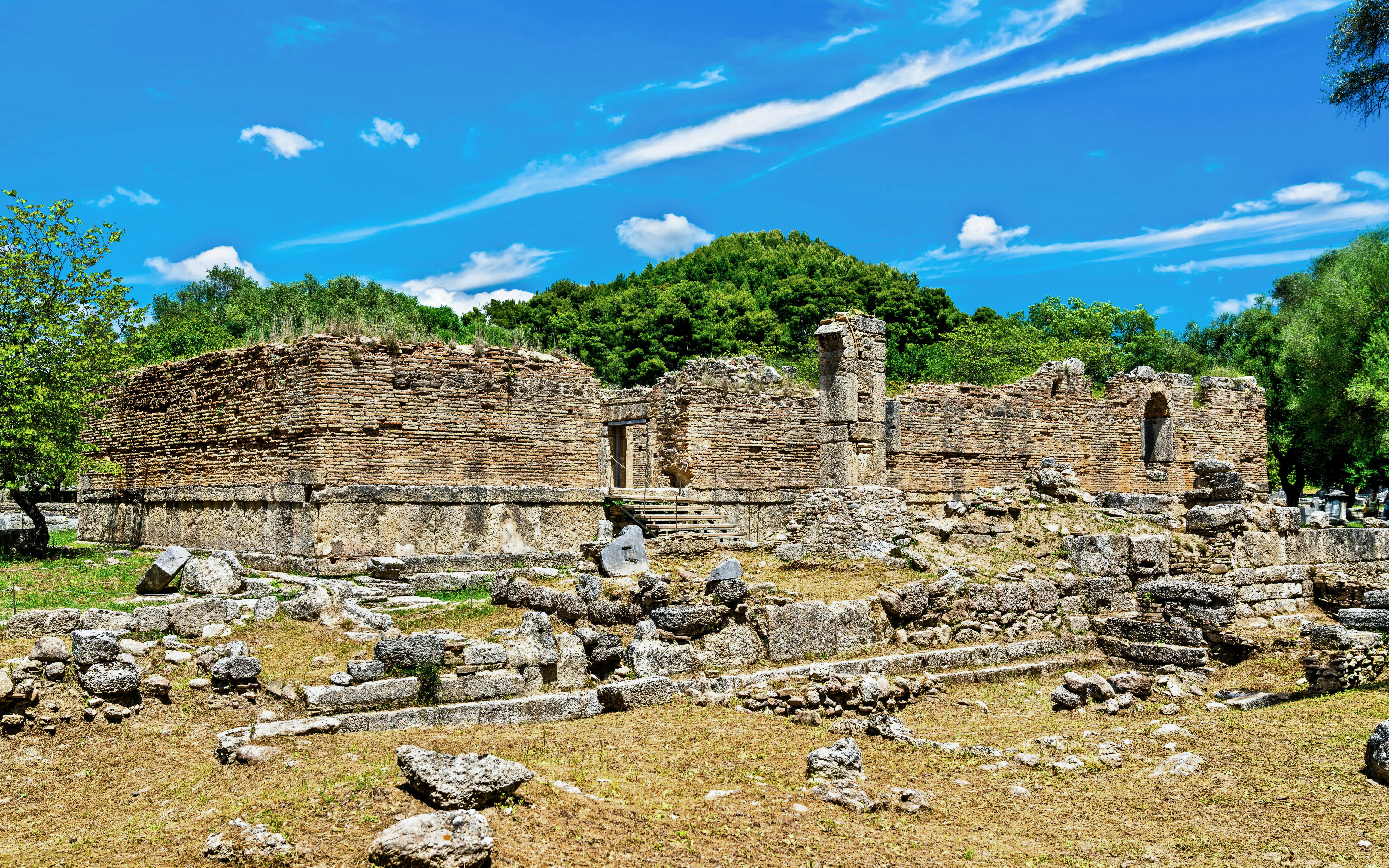 Ancient ruins at the Archaeological Site of Olympia, Greece, surrounded by greenery.