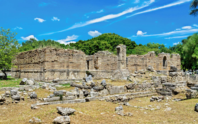 Ancient ruins at the Archaeological Site of Olympia, Greece, surrounded by greenery.