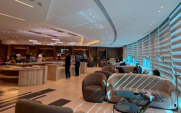 Couches and chairs in the Plaza Premium Lounge, Cairo, with guests relaxing and dining.