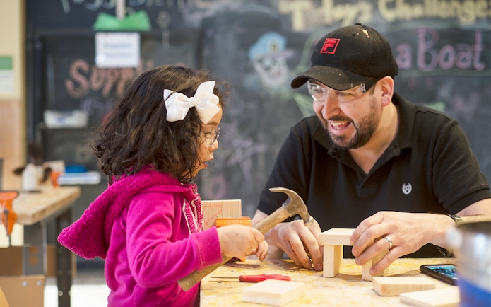 Child and adult building with wood at Chicago children's museum workshop.