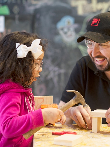 Child and adult building with wood at Chicago children's museum workshop.