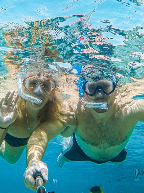 Couple snorkeling in clear waters on Baunei Coast guided boat tour.