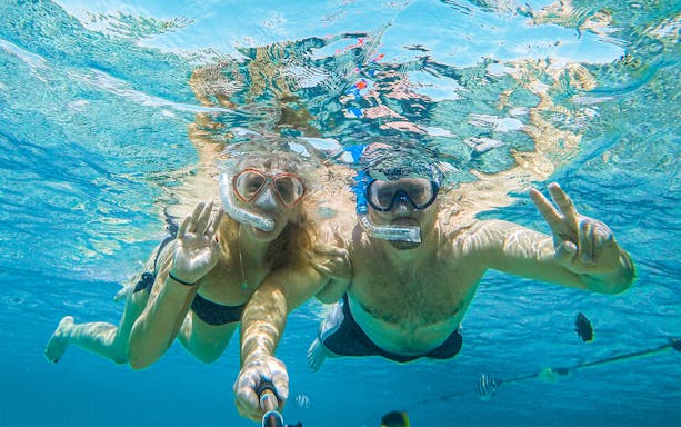 Couple snorkeling in clear waters on Baunei Coast guided boat tour.