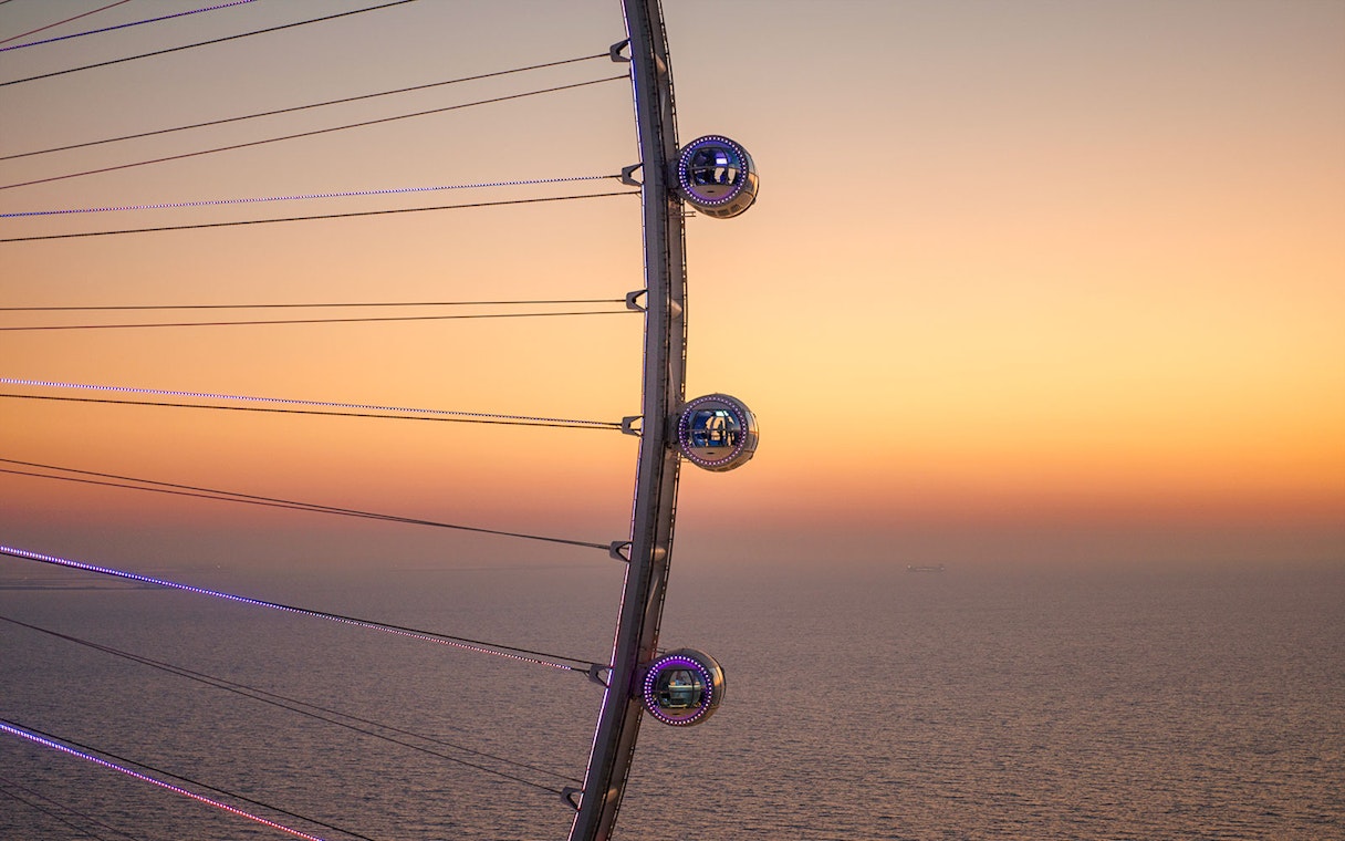 Ain Dubai pods overlooking the sea at sunset.