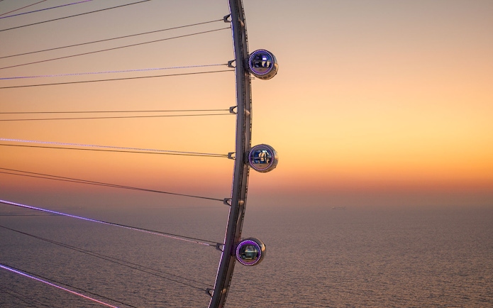 Ain Dubai pods overlooking the sea at sunset.