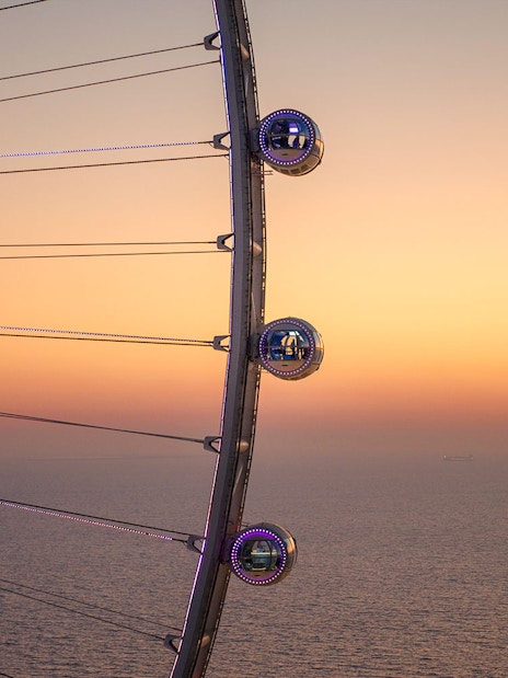 Ain Dubai pods overlooking the sea at sunset.