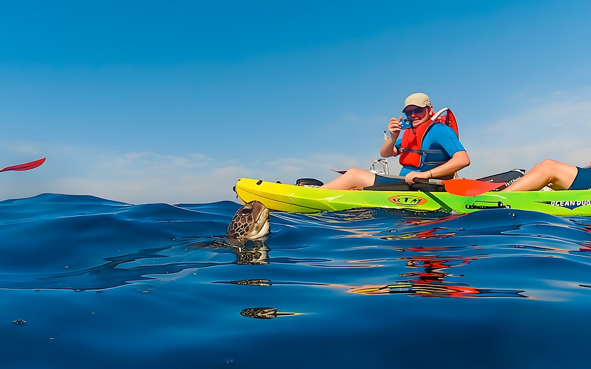 Tourist kayaking near a turtle in Tenerife waters.