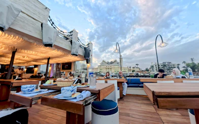 Nile Dahabiya dinner cruise with guests dining on deck, scenic river view in background.