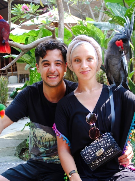 Couple with colorful birds at Lombok Wildlife Park, Indonesia.
