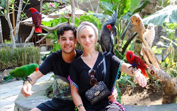 Couple with colorful birds at Lombok Wildlife Park, Indonesia.