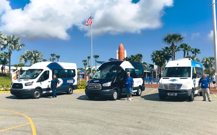 Shuttle vans for transfers to Kennedy Space Center with staff in front.