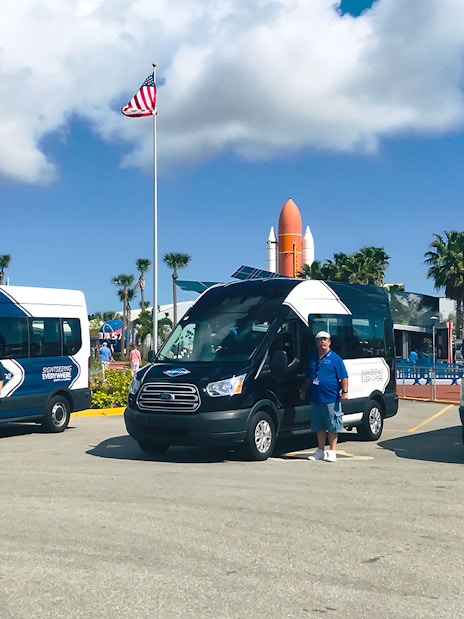 Shuttle vans for transfers to Kennedy Space Center with staff in front.