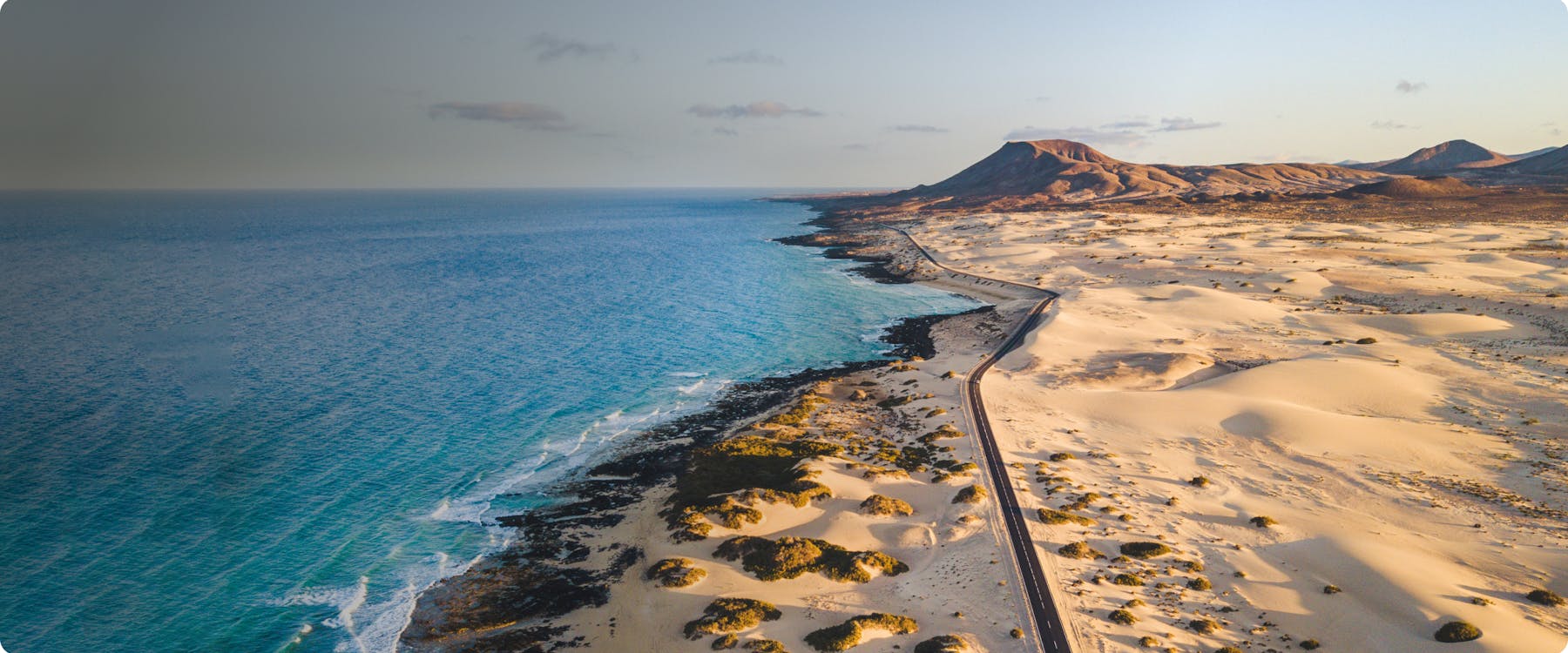 Aerial view of Fuerteventura coastline with sandy dunes and ocean.