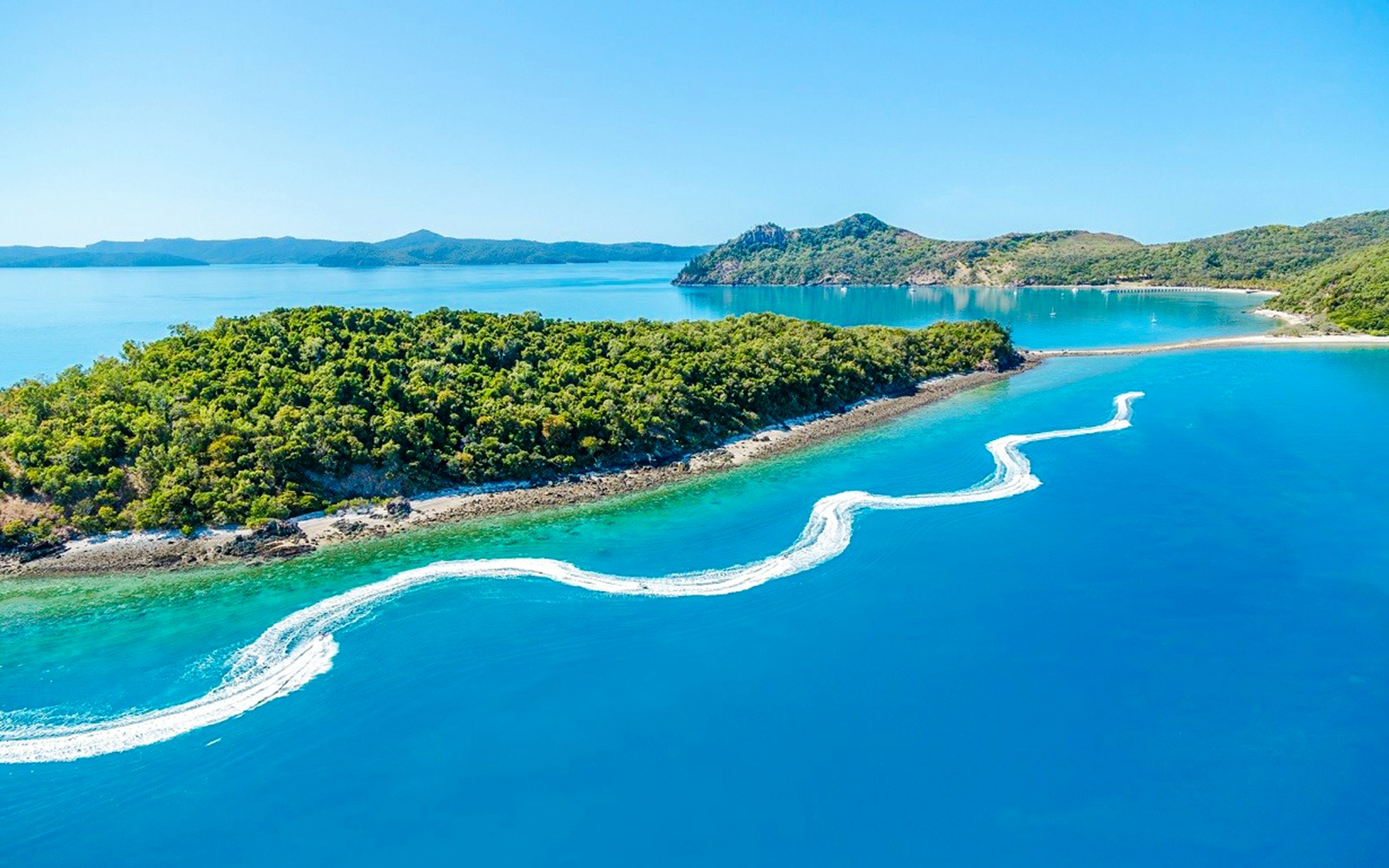 Aerial view of jetski trails near lush island in Whitsundays, Australia.