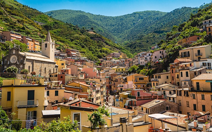 Colorful hillside village in Cinque Terre with church and terraced houses.